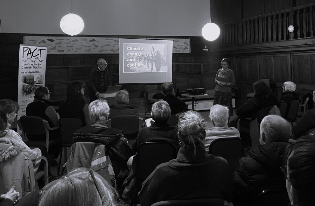 A man gives a talk to a crowded room.